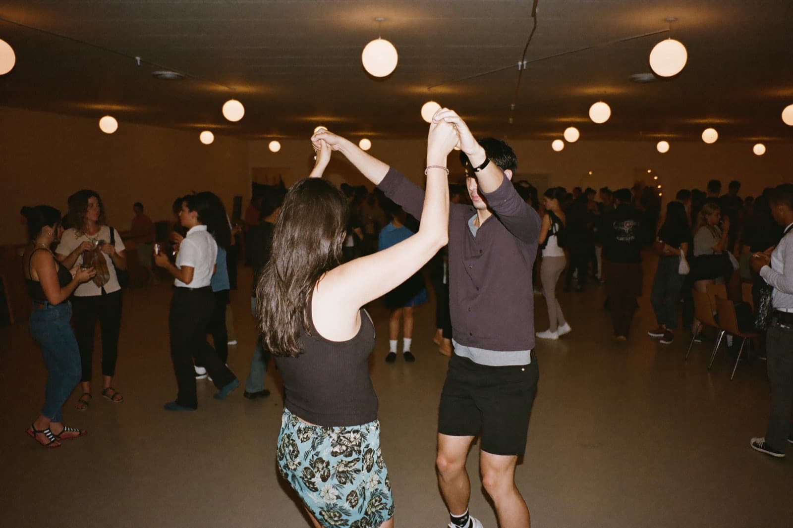 A couple mid-spin on a warm, crowded salsa social dance floor