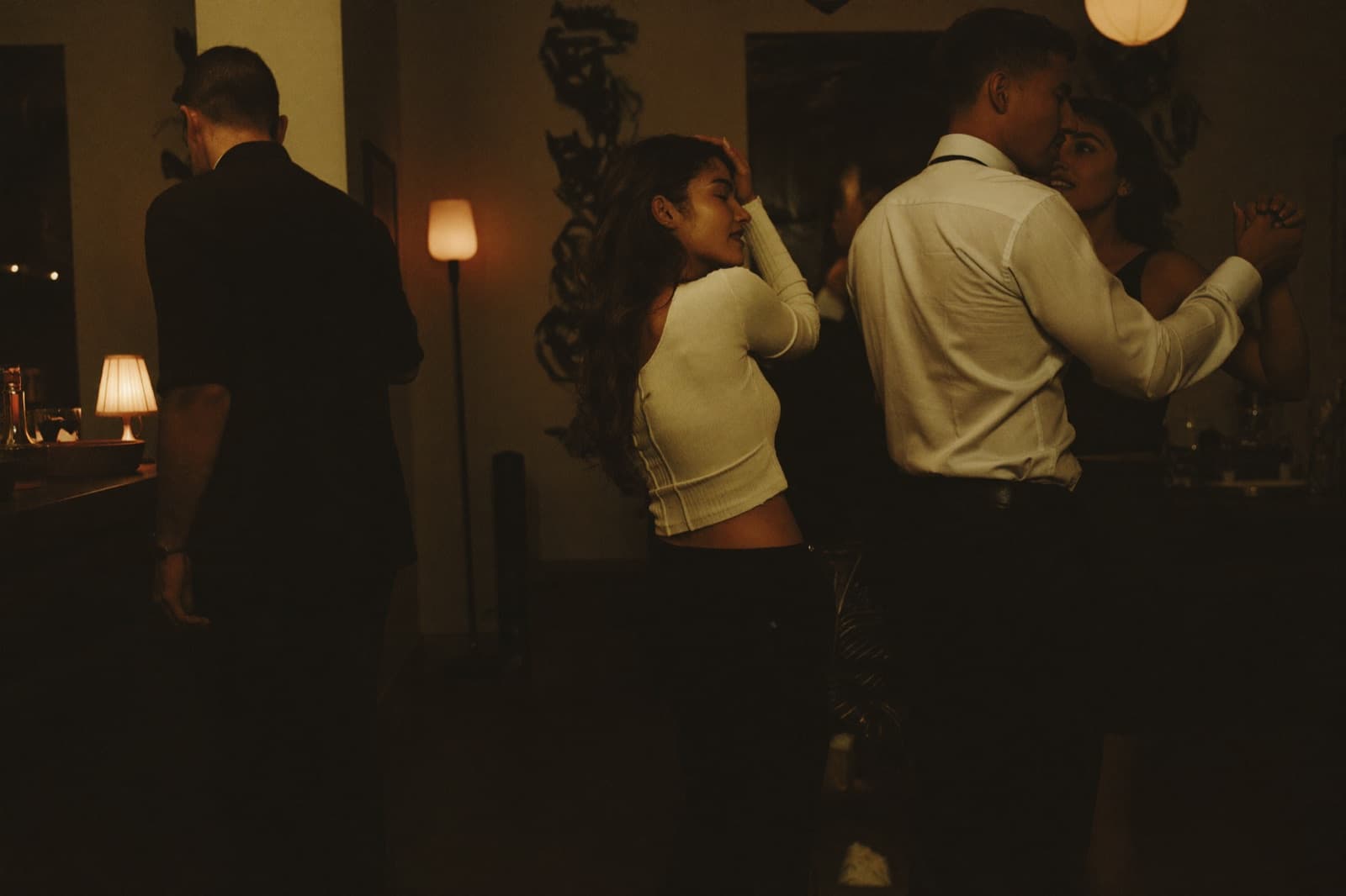 An intimate kizomba couple in a close embrace in dim warm light